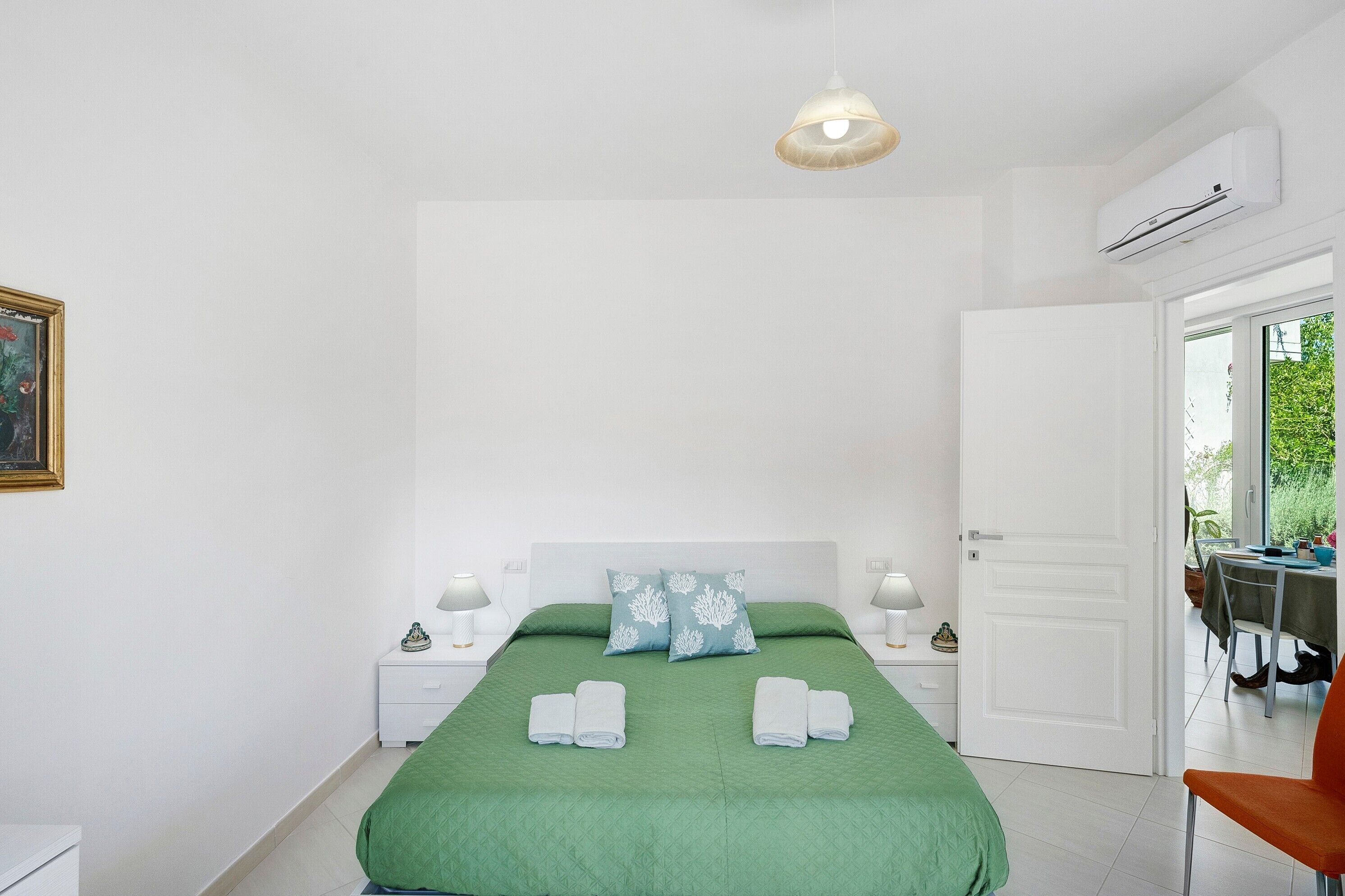 A bedroom with a bed, two nightstands, a door, and a window.