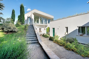 A modern building with a staircase leading to a second floor, surrounded by greenery and a paved pathway. - Apartment with Terrace and Lake View (Alvignano)
