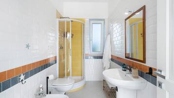 A bathroom with a shower, two sinks, and a toilet.