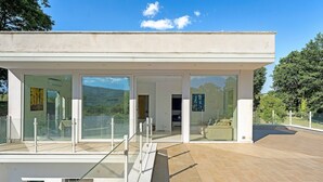 A modern house with a glass facade, a balcony, and a view of the surrounding landscape. - Apartment with Terrace and Lake View (Alvignano)