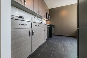 A modern kitchen with grey cabinetry, stainless steel appliances, and a tiled floor. - NYC Luxe Rentals  (New York)