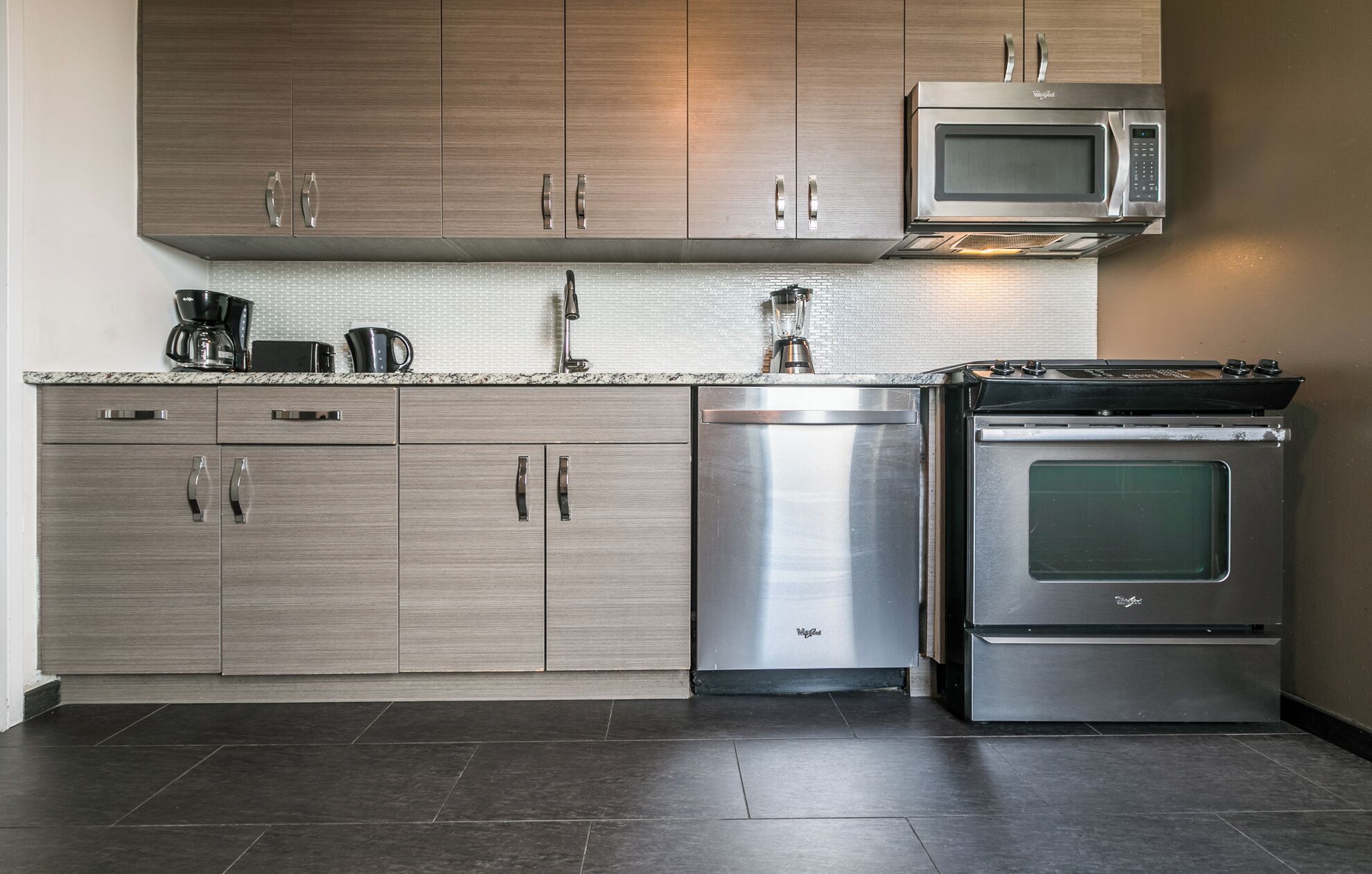 Eine moderne Küche mit Edelstahlgeräten, Holzschränken und einer Arbeitsplatte aus Granit.