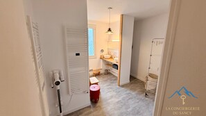 Un couloir étroit mène à une salle de bain équipée d’un lavabo, d’un miroir et d’un petit tabouret.