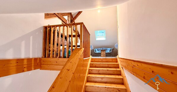 A wooden staircase with a view of a living room at the top.