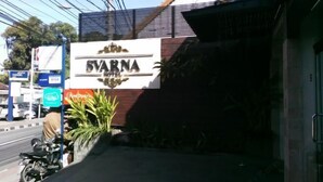 A hotel sign for 'SVARNA HOTEL' with a logo, a Visa sign, and a nearby motorcycle. - Svarna Hotel (Bali)
