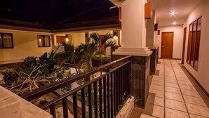 A hotel corridor with a tiled floor, a balcony with a railing, and a door at the end. - Svarna Hotel (Bali)