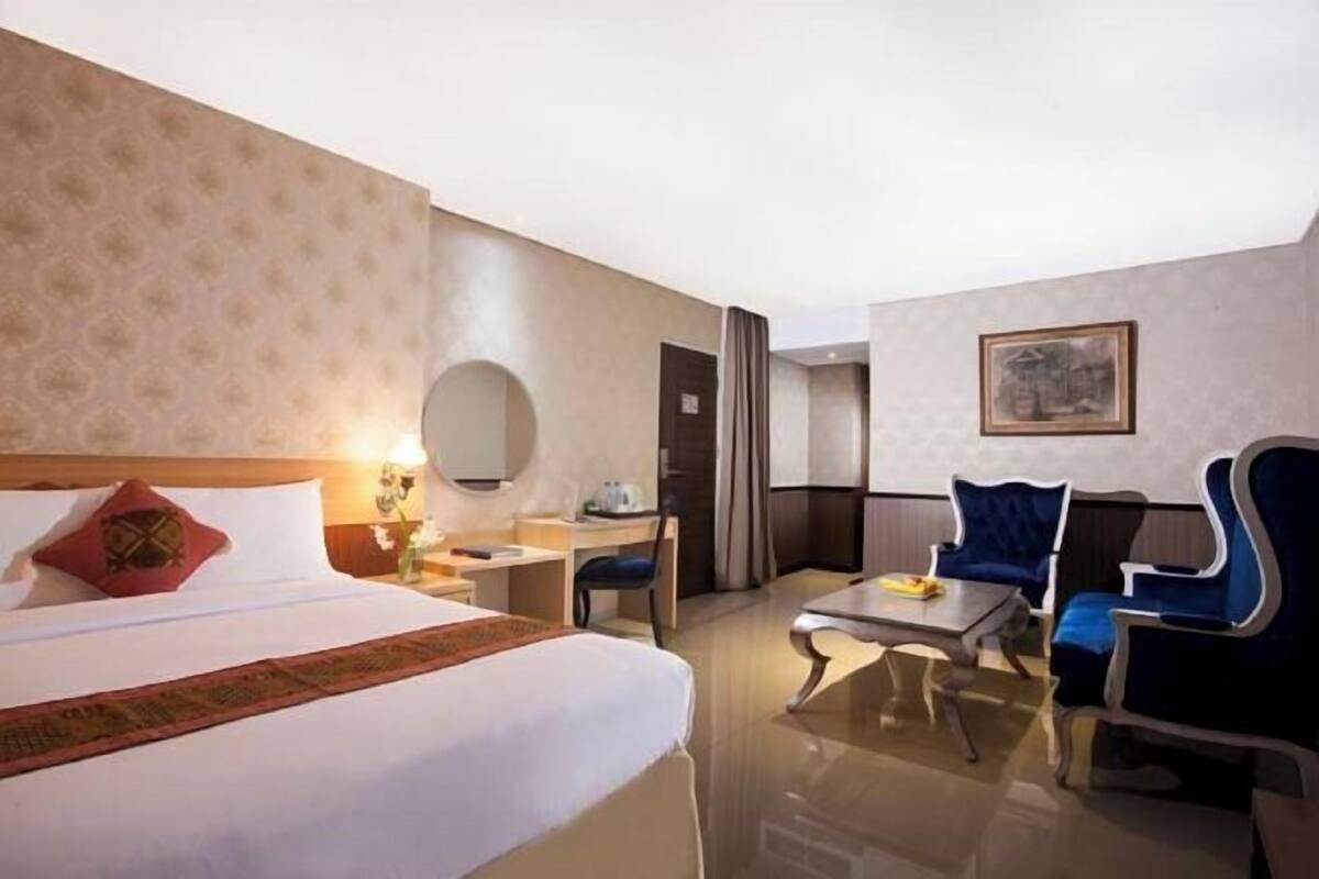 Een hotelkamer met een bed, een bureau, een stoel, een tafel en een spiegel.