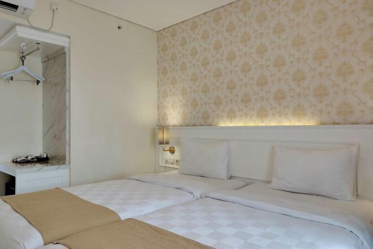 Une chambre d’hôtel avec un lit, une table de chevet, un porte-manteau mural et un papier peint à motifs.