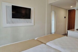 Une chambre d’hôtel avec deux lits, un téléviseur fixé au mur et un miroir.