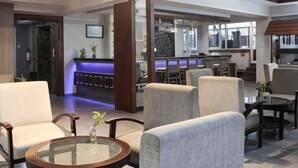 Un hall d’hôtel comprenant des espaces de détente, un comptoir d’accueil et un bar.