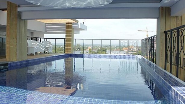 Une piscine avec un bord carrelé, une terrasse en bois et une vue sur le paysage environnant.