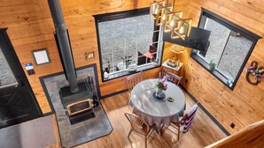 A wooden interior with a dining area, large windows, and a fireplace. - Grizzly Bear Cabin # 2. (Central Kootenay)