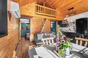 Un intérieur en bois comprenant une chambre en mezzanine, un coin repas et une cuisine.