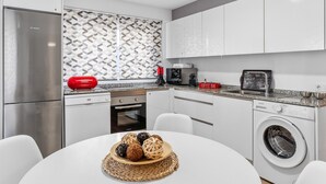 Une cuisine moderne équipée d’un réfrigérateur Bosch, d’un four à micro-ondes, d’un coin café et d’un lave-linge.