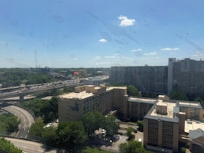 A high-rise building with a flat roof, surrounded by greenery and other buildings.