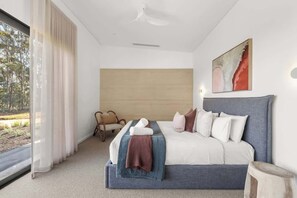 Een moderne slaapkamer met een groot bed, uitzicht op de omgeving en een plafondventilator.