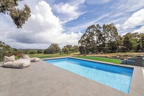 A swimming pool with a view of trees and hills in the background.