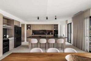 Una cucina moderna con isola centrale, sgabelli da bar e elettrodomestici integrati.