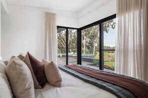 Una camera da letto con un'ampia finestra, un letto con cuscini e vista sull'esterno.