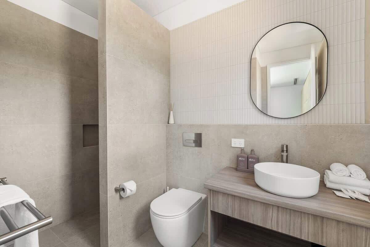 A modern bathroom with a toilet, bidet, and a large mirror.