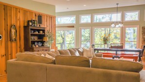 Ein Wohnzimmer mit Ecksofa, Holzschränken und einem Essbereich mit einer Bank und einem Tisch.