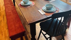 Ein Essbereich mit einem Holztisch, gedeckt für sechs Personen, umgeben von Stühlen und einer Bank an einer Seite.