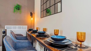 Un comedor moderno con una larga mesa de madera, vajilla azul y dorada, y un banco tapizado en azul.