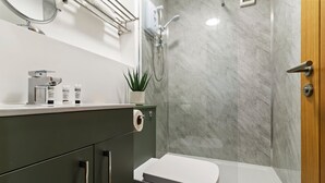A modern bathroom with a shower, toilet, and vanity. - Pippin - BRAND NEW stylish studio apartment in the hub of Worcester City Centre (Worcestershire)