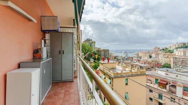 Un balcón con vista a un paisaje urbano, un armario y un aire acondicionado instalado en la pared.