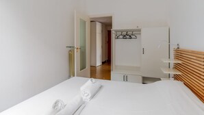 Una habitación de hotel con cama, armario, espejo y cabecera de madera.