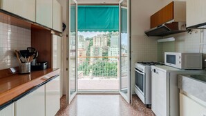 Una cocina con vista a edificios, microondas, estufa y armarios.