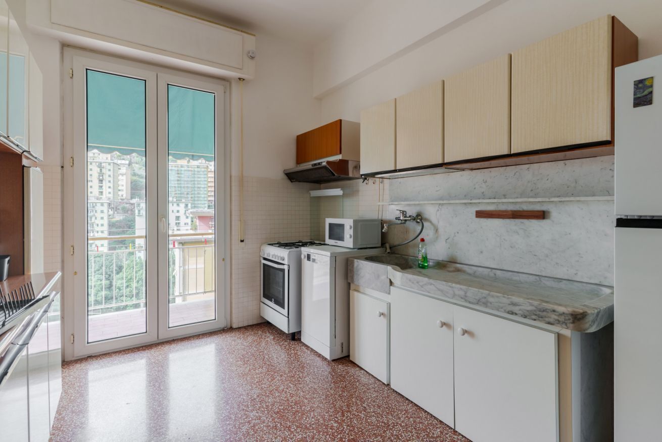 A kitchen with white cabinets, a microwave, a stove, and a sink.
