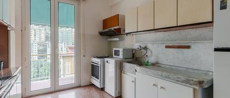 A kitchen with white cabinets, a microwave, a stove, and a sink.