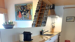 Eine Küche mit weißen Schränken, einer Holz Arbeitsplatte, einem Spülbecken und einer Leiter zu einem erhöhten Bereich.