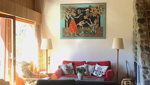 Ein gemütliches Wohnzimmer mit einem roten Sofa, einem Gemälde darüber und einer Steinwand.