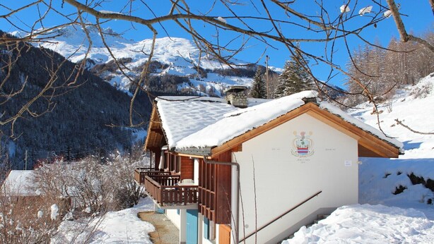 Eine Chalet mit Holzbalkon, Steinofen und Bergblick.