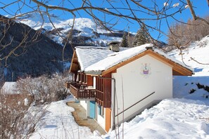 A chalet with a wooden balcony, a stone chimney, and a mountain backdrop. - Chalet Kiri  8 personnes sur les hauteurs d'Evolène (Evolène)