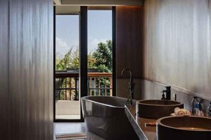 Une salle de bain moderne avec une baignoire sur pieds, deux vasques et une vue sur la verdure environnante.