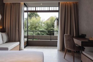 A bedroom with a bed, a desk, and a view of a balcony with a railing. - The Akasha Canggu Hotel (Bali)