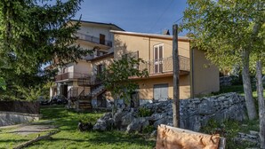 Un edificio de dos plantas con balcón, pared de piedra y césped.
