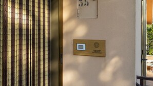 Entrada de un edificio con una puerta numerada, una placa y una reja metálica.