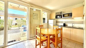 Une cuisine compacte avec un coin repas, une porte-fenêtre coulissante donnant sur un patio et une vue sur un quartier résidentiel.