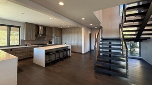 Une cuisine moderne dotée d’un îlot central, d’un escalier et offrant une vue sur l’extérieur.