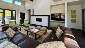 Un salon moderne comprenant un canapé, des fauteuils, une table basse, une cheminée et un téléviseur.