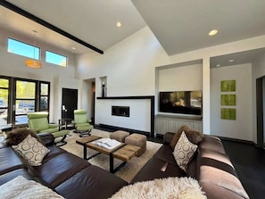 A modern living room with a sofa, chairs, a coffee table, a fireplace, and a TV.