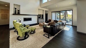 Un salon spacieux doté d’une cheminée, de sièges confortables et de grandes fenêtres.