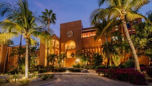A hotel with a central courtyard, palm trees, and a warm-toned building facade. - Beachfront 1-bedroom apartment in delightful Los Cabos, Resort Access (San José del Cabo)