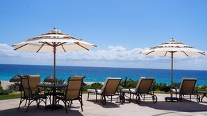 A patio with outdoor seating and umbrellas overlooking the ocean. - Beachfront 1-bedroom apartment in delightful Los Cabos, Resort Access (San José del Cabo)