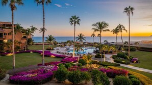 A resort with a pool, palm trees, and a view of the ocean at sunset. - Beachfront 1-bedroom apartment in delightful Los Cabos, Resort Access (San José del Cabo)