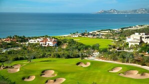 A golf course with bunkers, a clubhouse, and a view of the sea. - Beachfront 1-bedroom apartment in delightful Los Cabos, Resort Access (San José del Cabo)